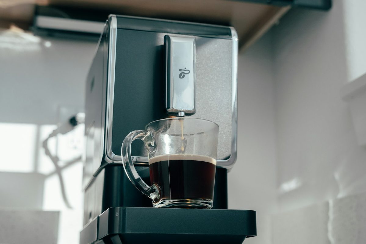 Kaffeevollautomat mit Glastasse Kaffee auf der Arbeitsplatte