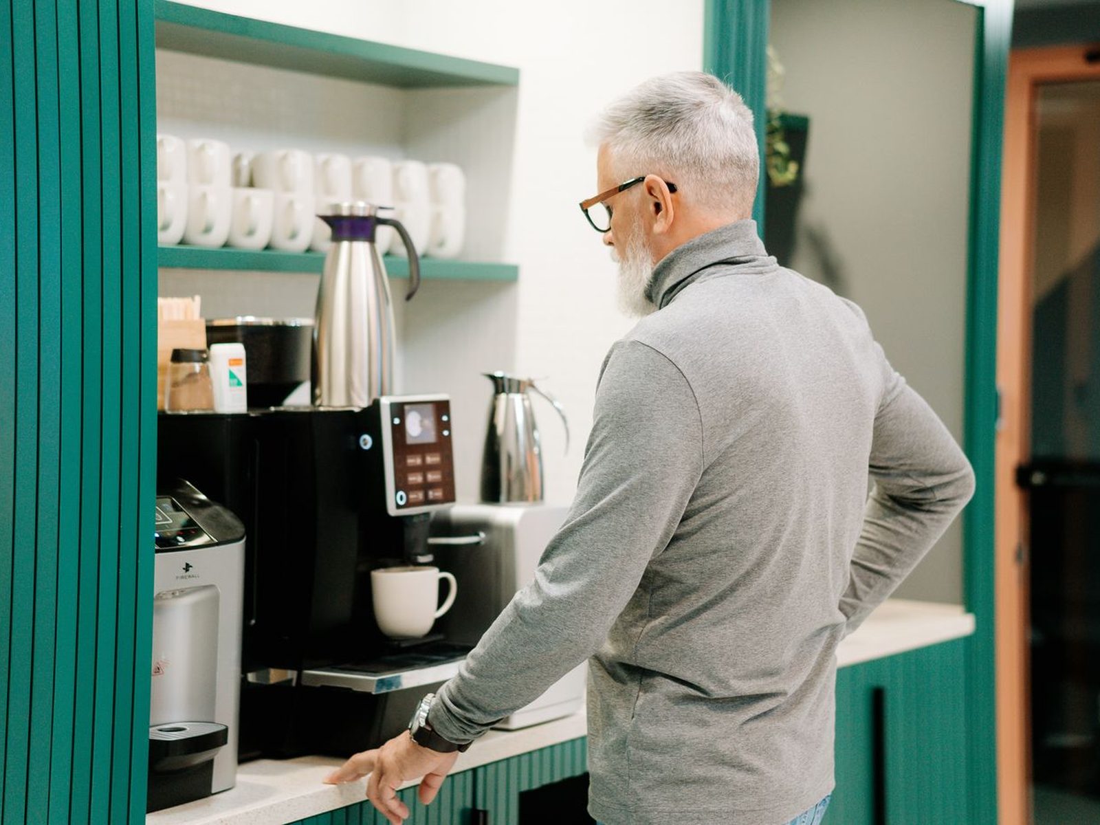 Mann bedient einen Kaffeevollautomaten in der Küche